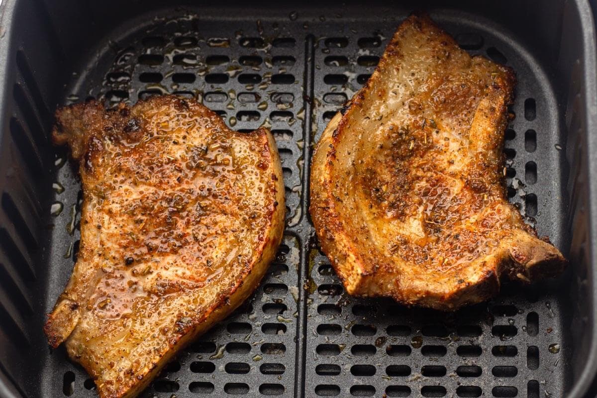 2 cooked pork chops in air fryer basket