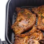 2 cooked pork chops in air fryer basket