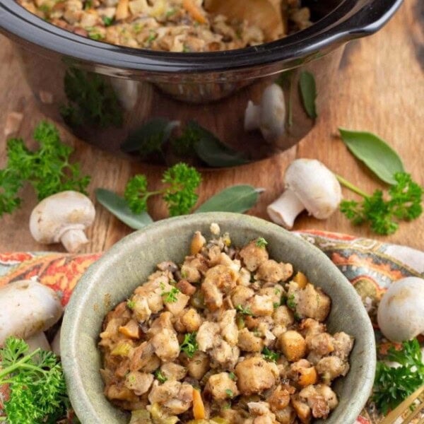 stuffing in a green bowl in front of black crock with garnishes
