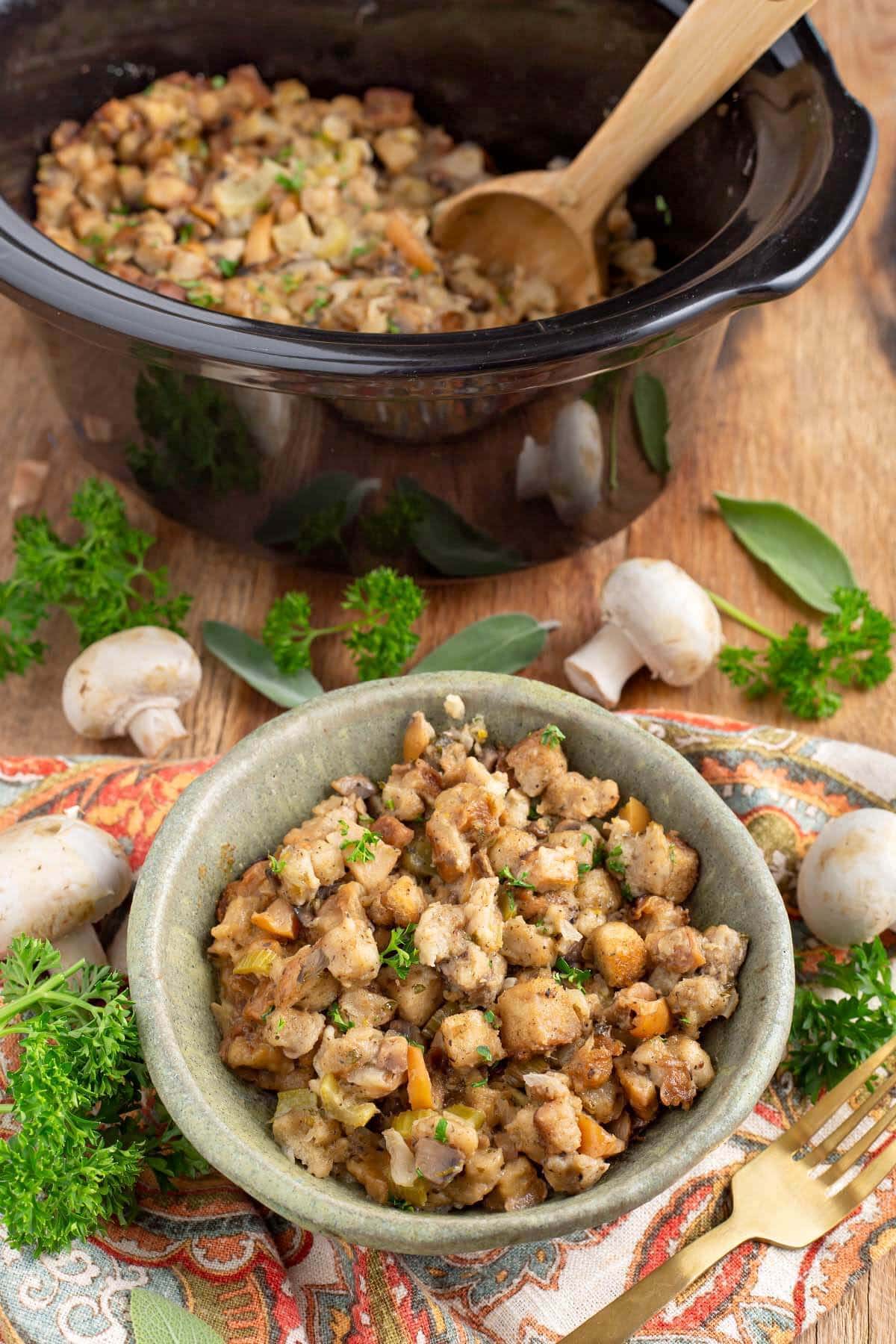 easy slow cooker stuffing in a green bowl in front of black crock with garnishes