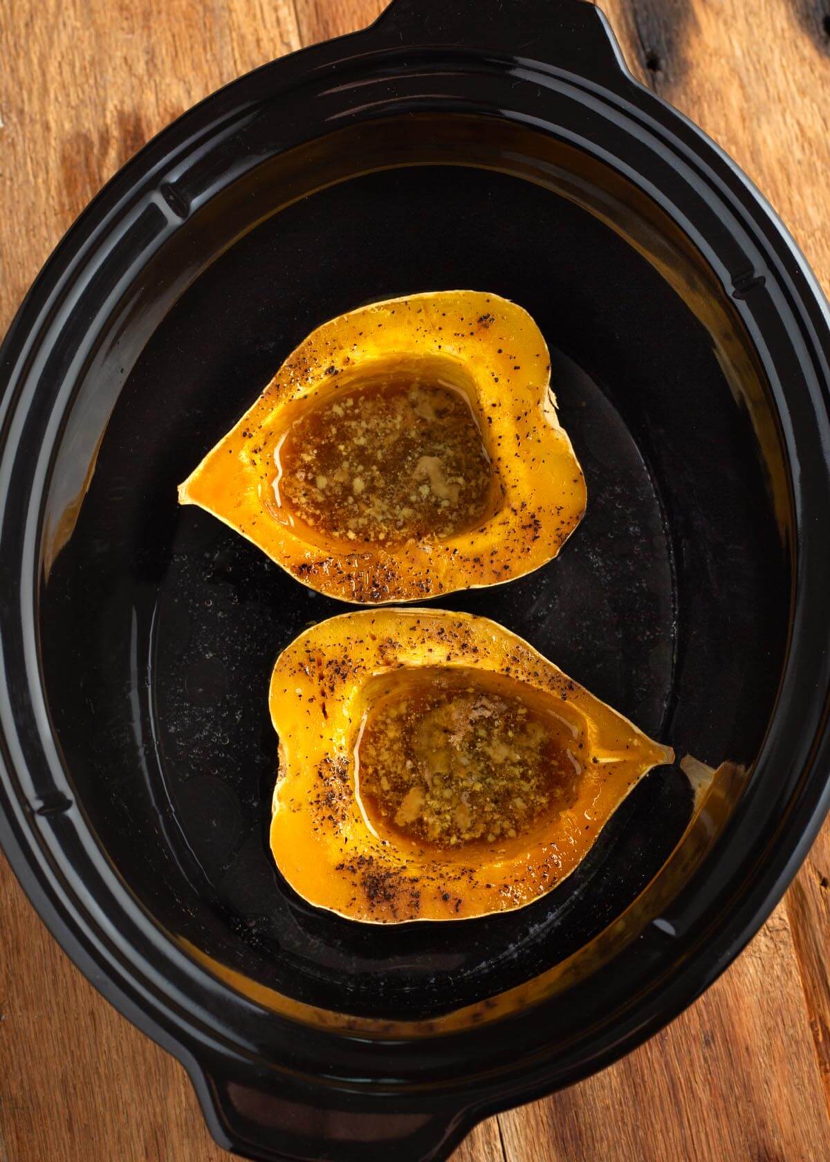 2 acorn squash halves in a black crock