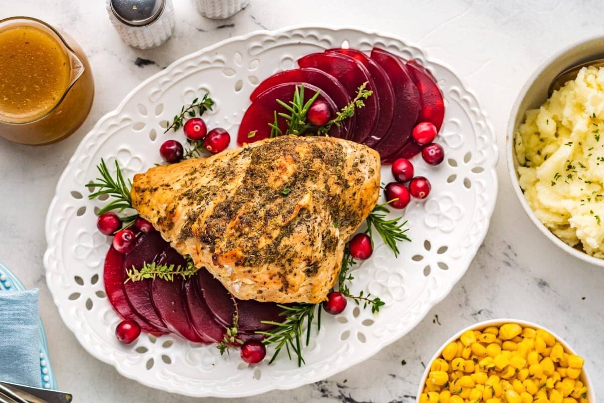 unsliced turkey breast on a white platter with cranberries