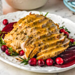 sliced turkey breast with gravy on a white plate with cranberries