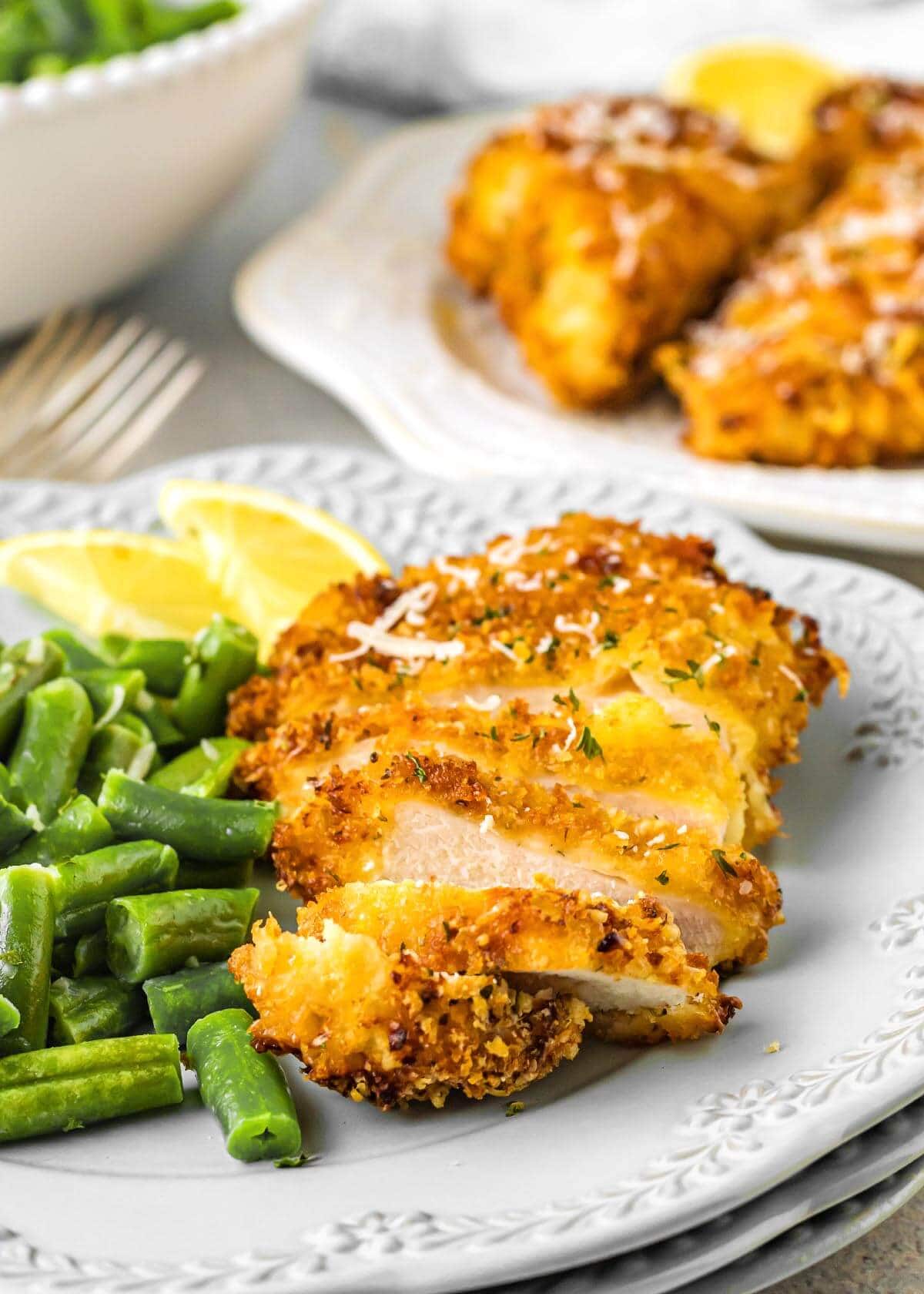 Air Fryer Parmesan Chicken sliced on a plate with green beans
