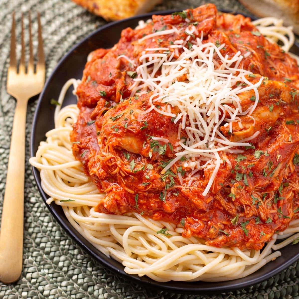 Chicken Cacciatore on a black plate on noodles