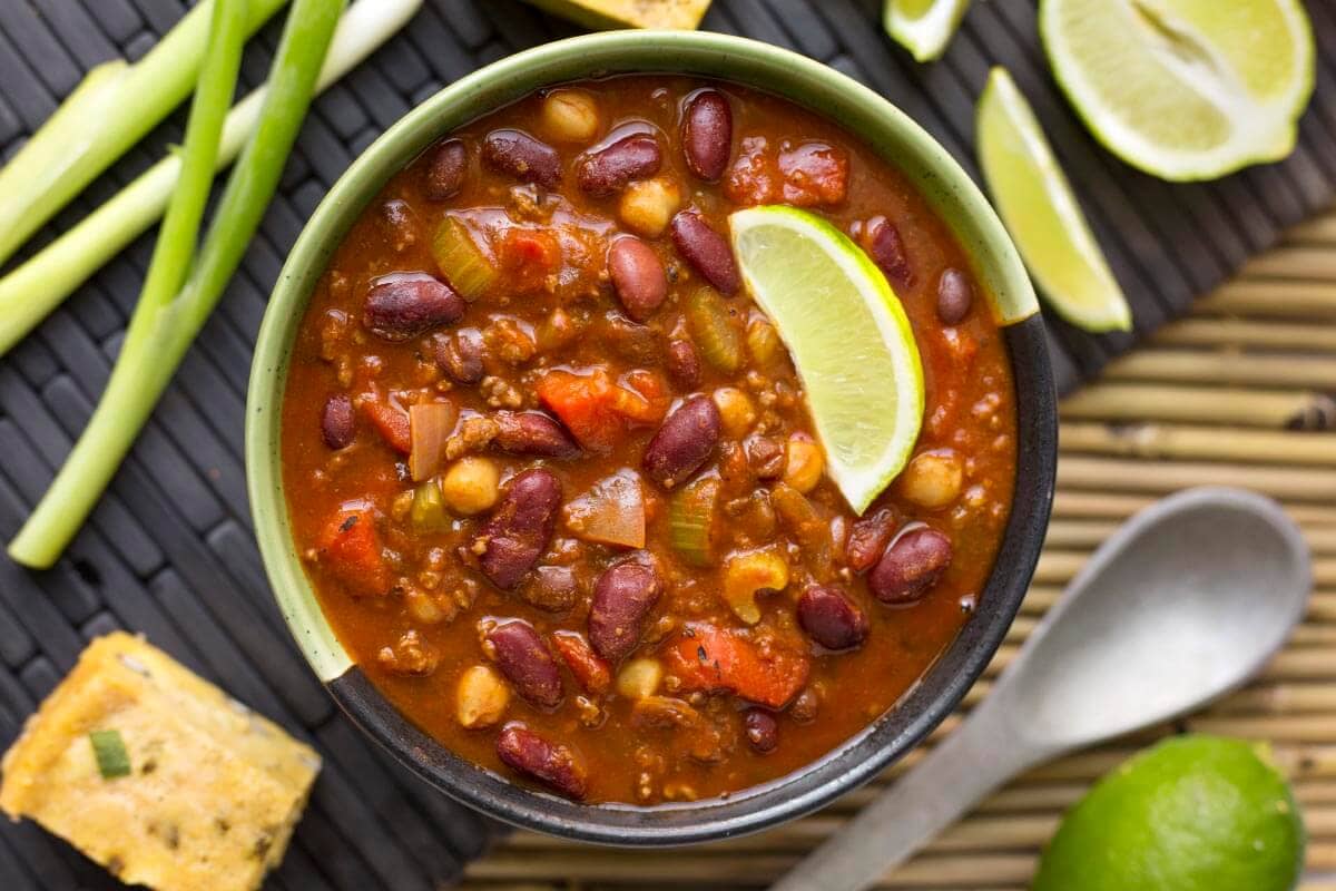 a bowl of chili with lime wedge.