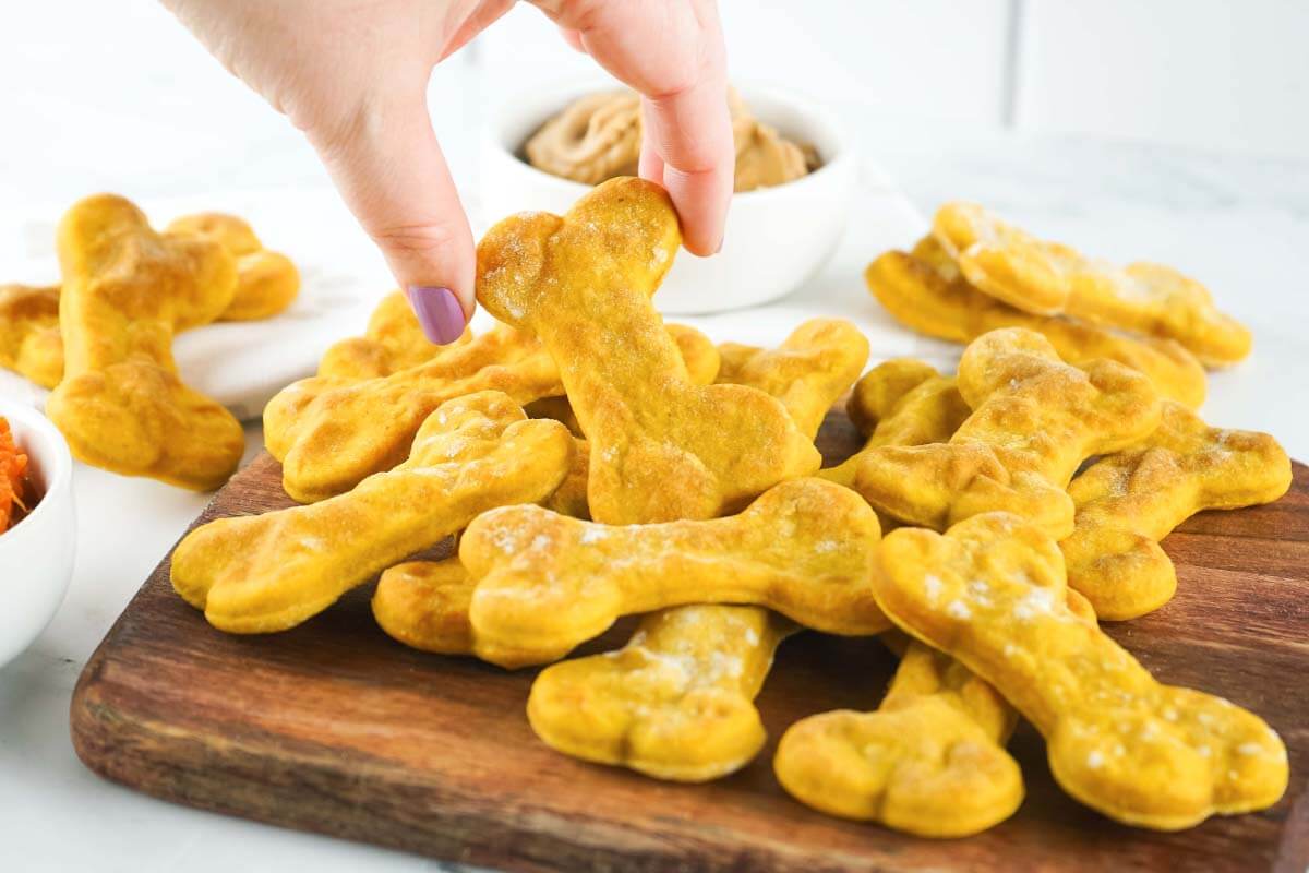 Air Fryer Dog Treats on a board with hand holding one