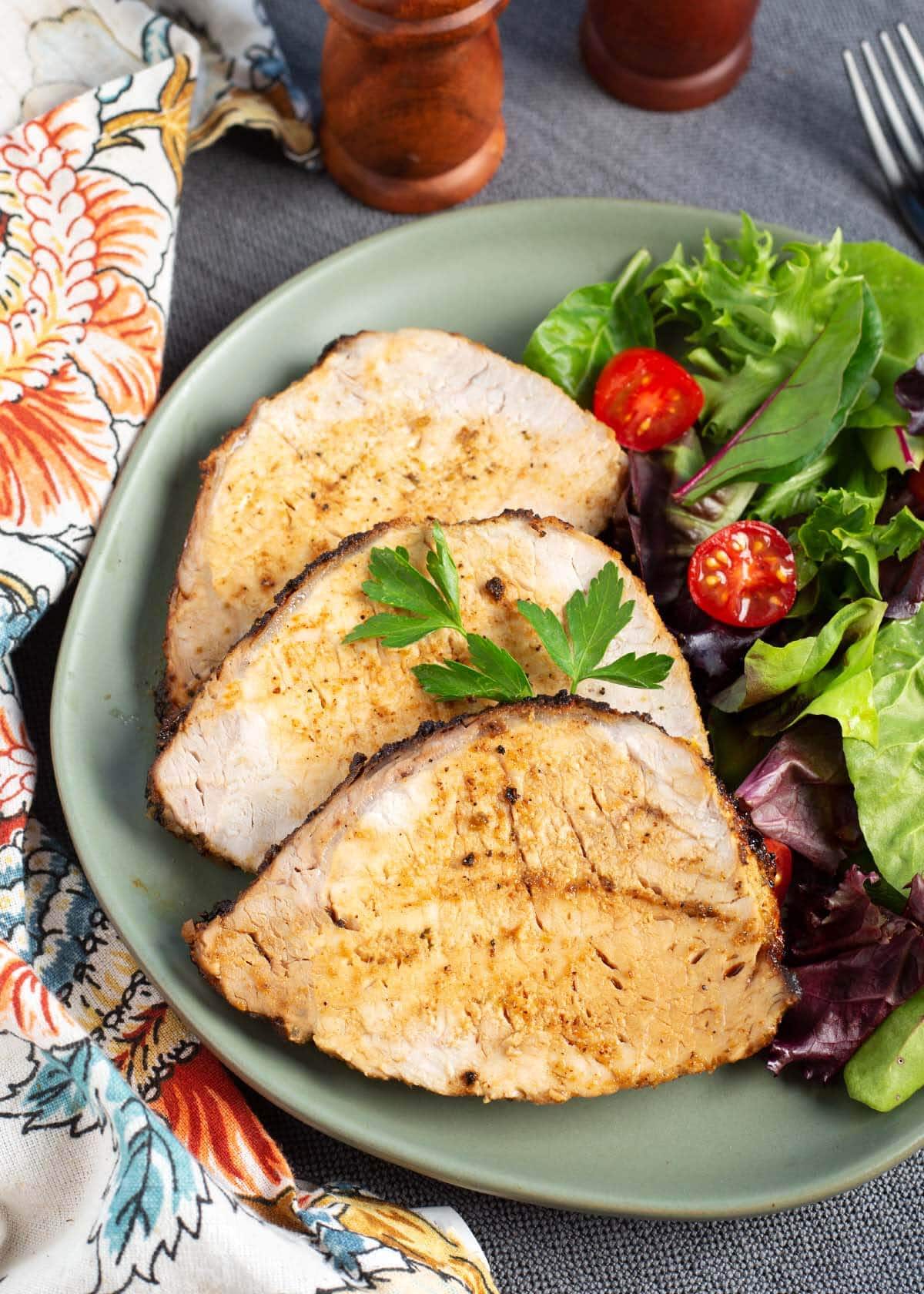 Air Fryer Pork Loin Roast slices on a plate with salad.