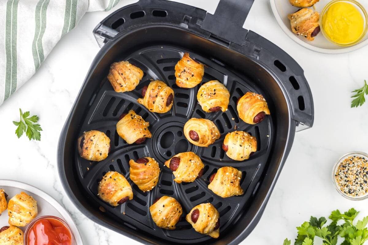 cooked Air Fryer Pigs in a Blanket in air fryer basket.