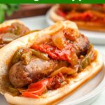 sausage and peppers in a bun on white plate.