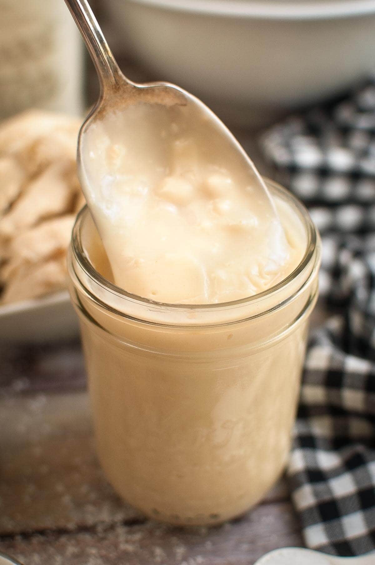 Homemade Condensed Cream of Chicken Soup in a jar with some on a spoon.