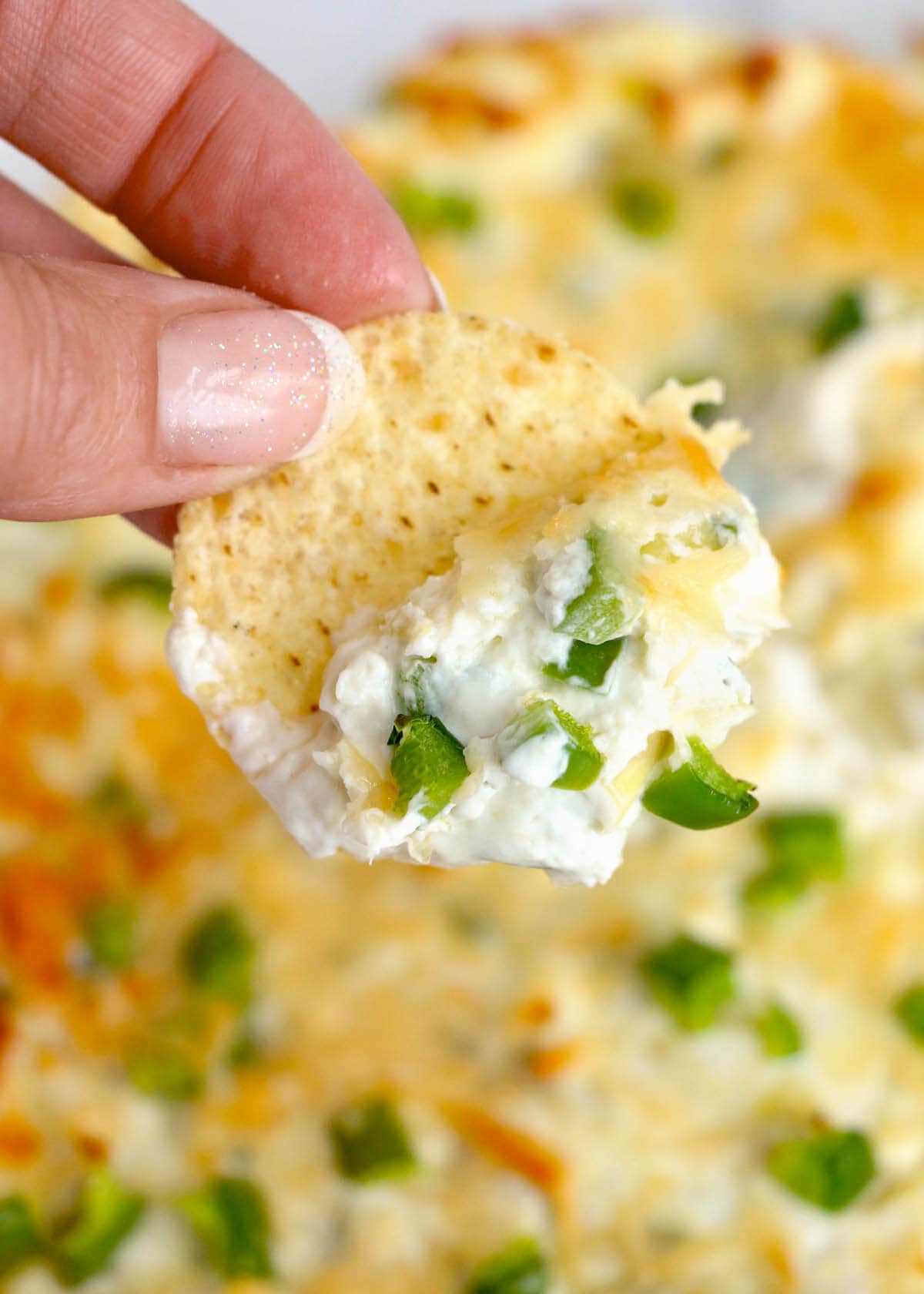 hand holding chip in Artichoke Jalapeño Dip.