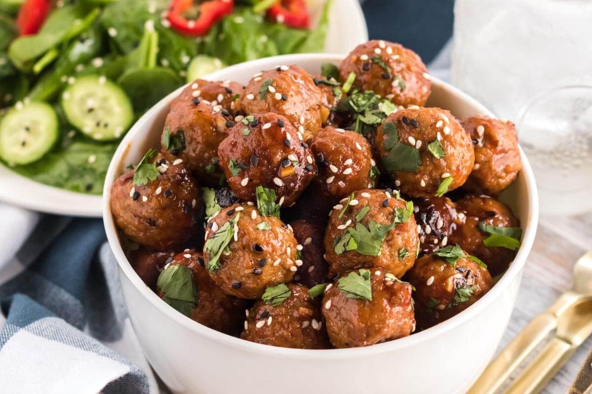 meatballs in a white bowl with sesame seeds