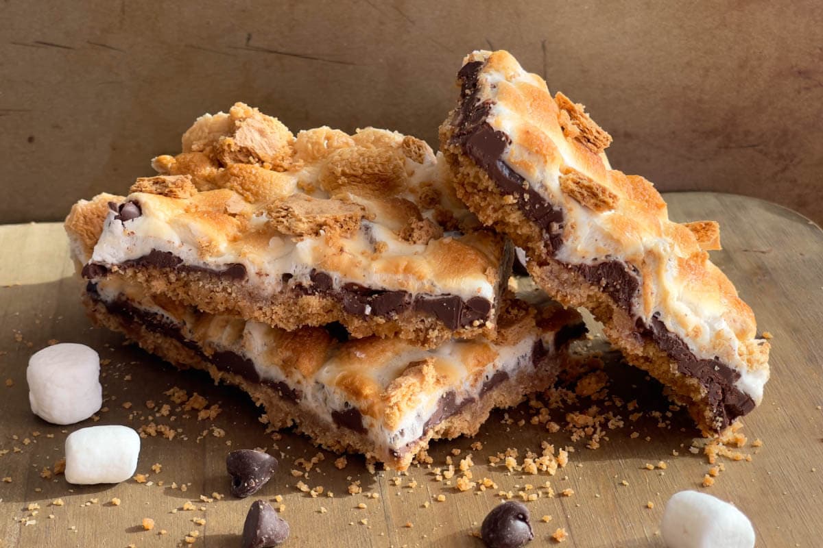 3 S'mores Bars stacked on a wood board.