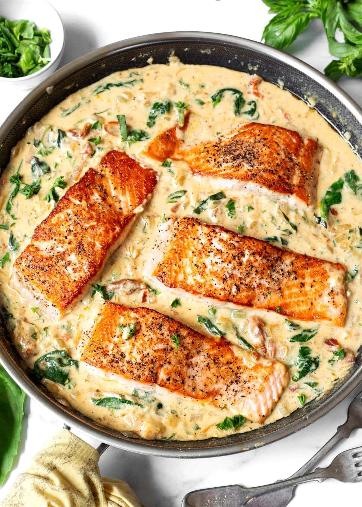 4 Creamy Garlic Tuscan Salmon fillets in a pan of sauce.