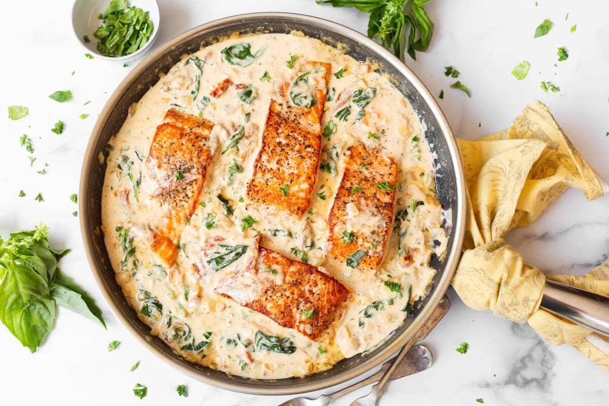 4 Salmon fillets in a pan of sauce.