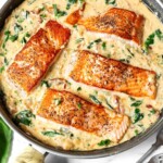 4 Creamy Garlic Tuscan Salmon filets in a pan of sauce.