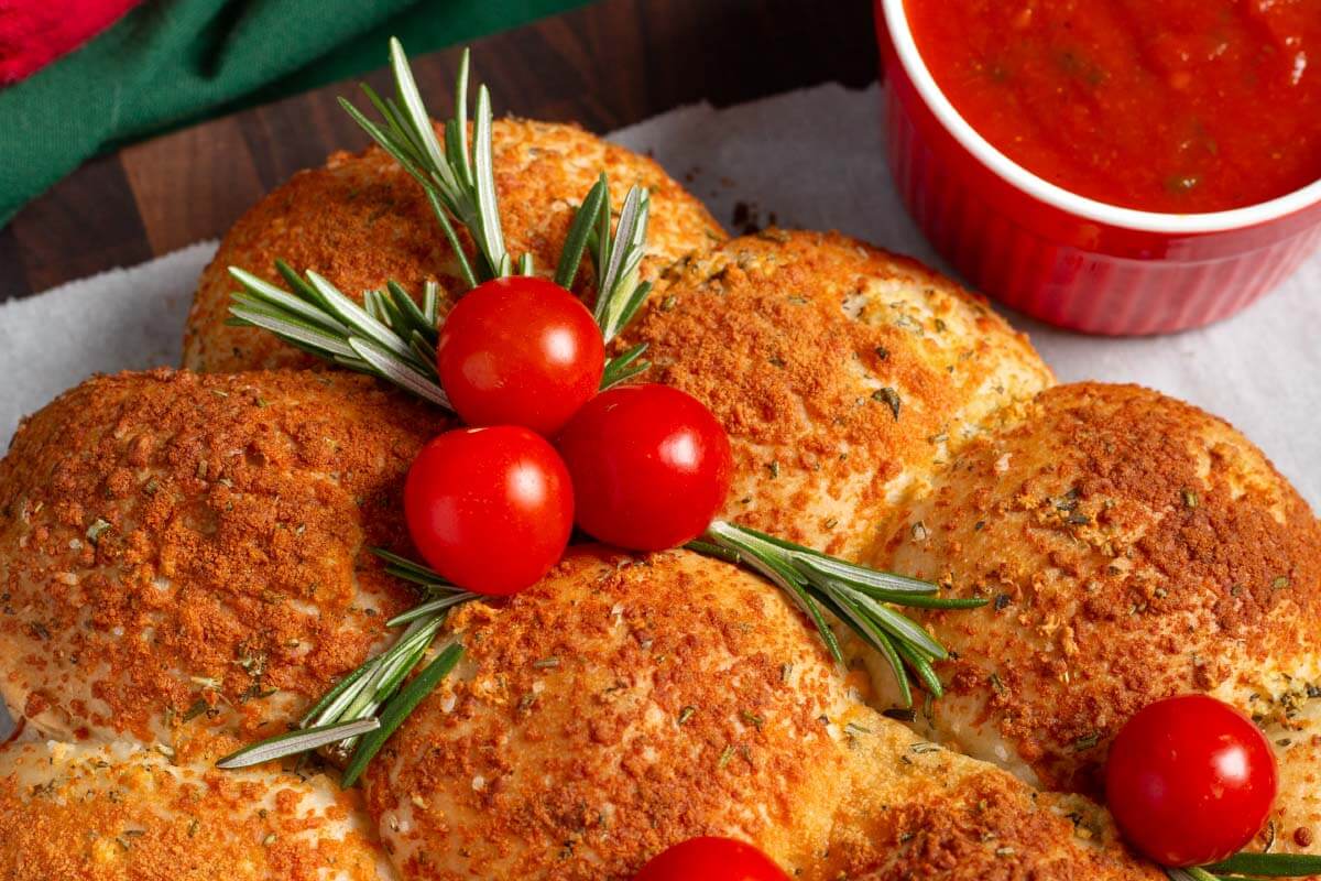 Dinner Roll Christmas Tree Appetizer closeup with cherry tomatoes and rosemary sprigs.