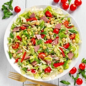 Italian Chopped Salad on white plate with tomatoes, basil, salami, lettuce