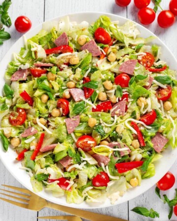 Italian Chopped Salad on white plate with tomatoes, basil, salami, lettuce