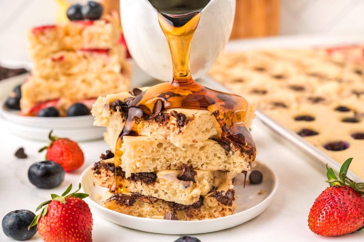 Sheet Pan Pancakes on white plate with syrup pouring over top.