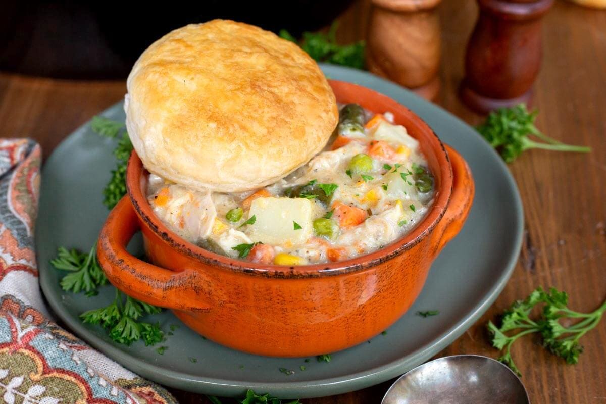Slow Cooker Chicken Pot Pie in an orange bowl with biscuit on top.