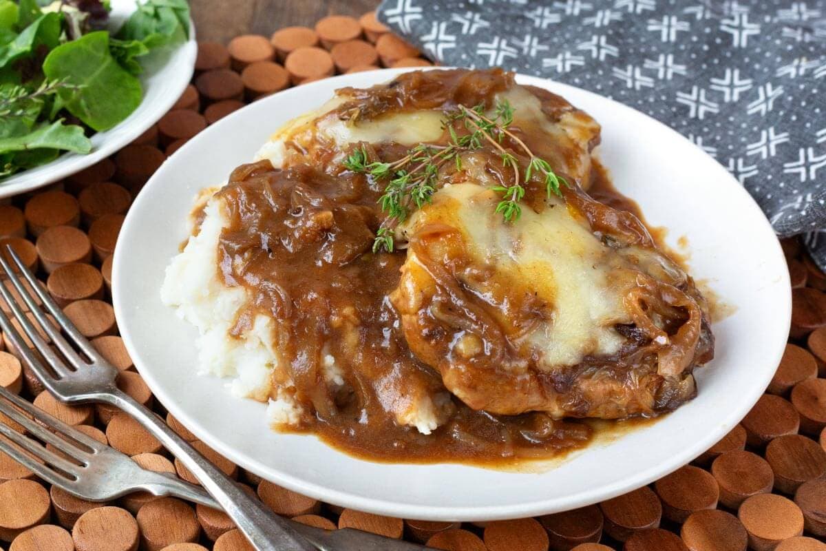 Slow Cooker French Onion Pork Chops and mashed potatoes on white plate.