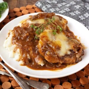 Slow Cooker French Onion Pork Chops and mashed potatoes on white plate.