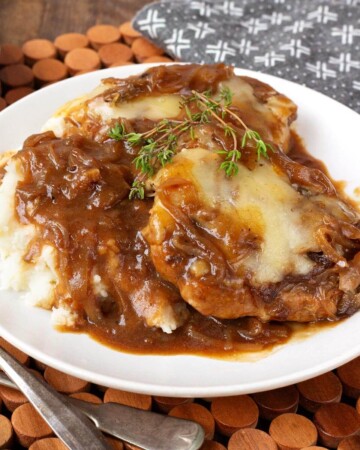 Slow Cooker French Onion Pork Chops and mashed potatoes on white plate.