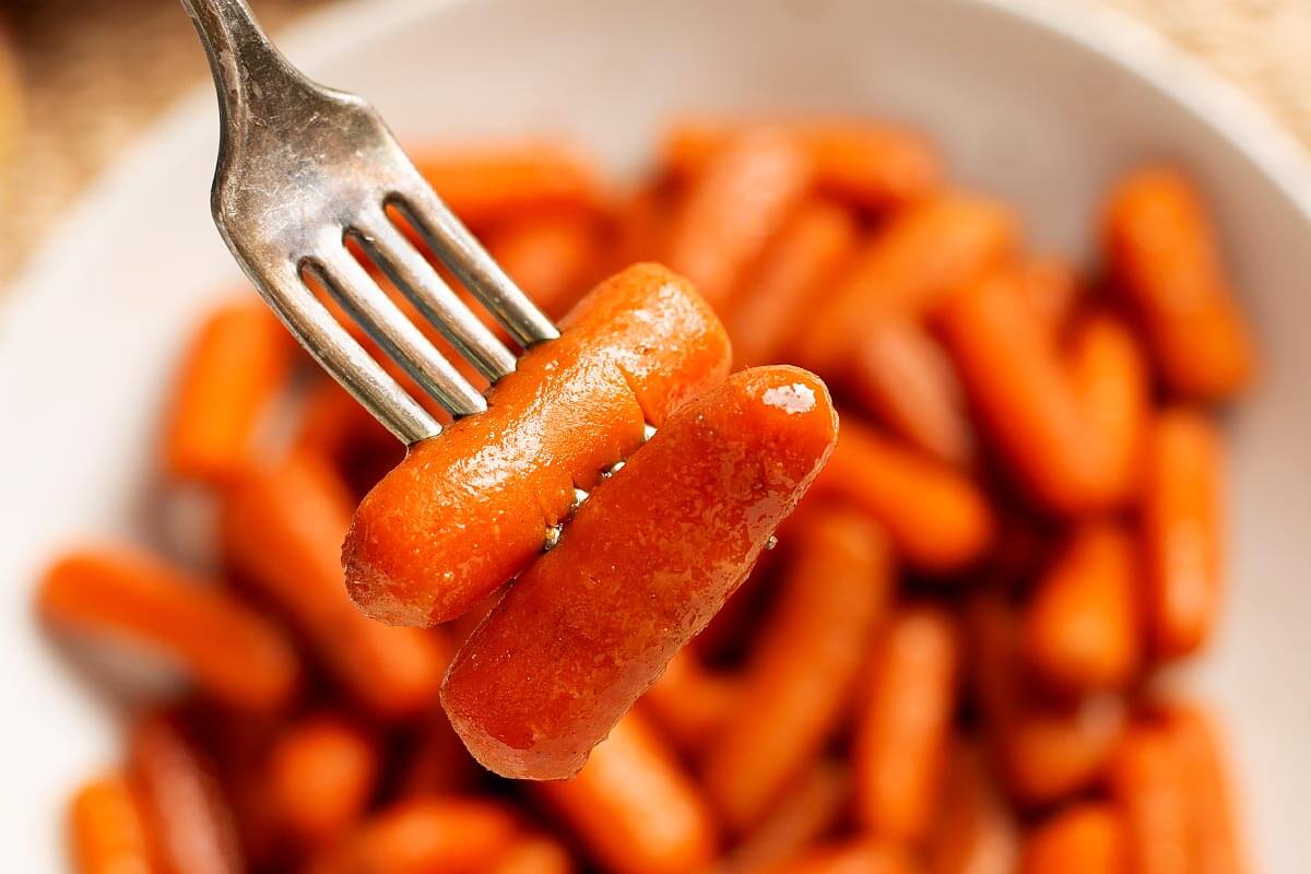 Slow Cooker Maple Brown Sugar Carrots on a fork over bowl