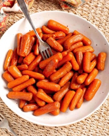 Slow Cooker Maple Brown Sugar Carrots in a white bowl with fork.