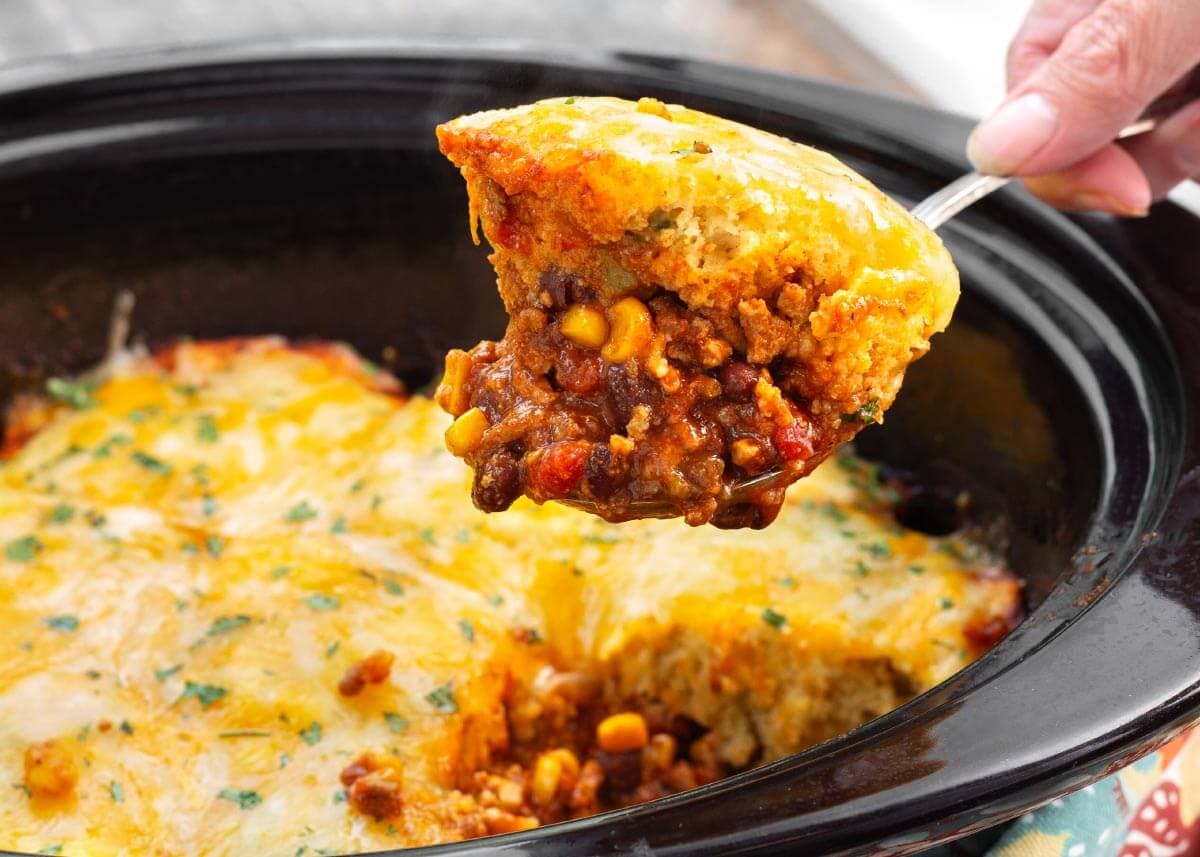 Slow Cooker Tamale Pie on a spoon above crock.