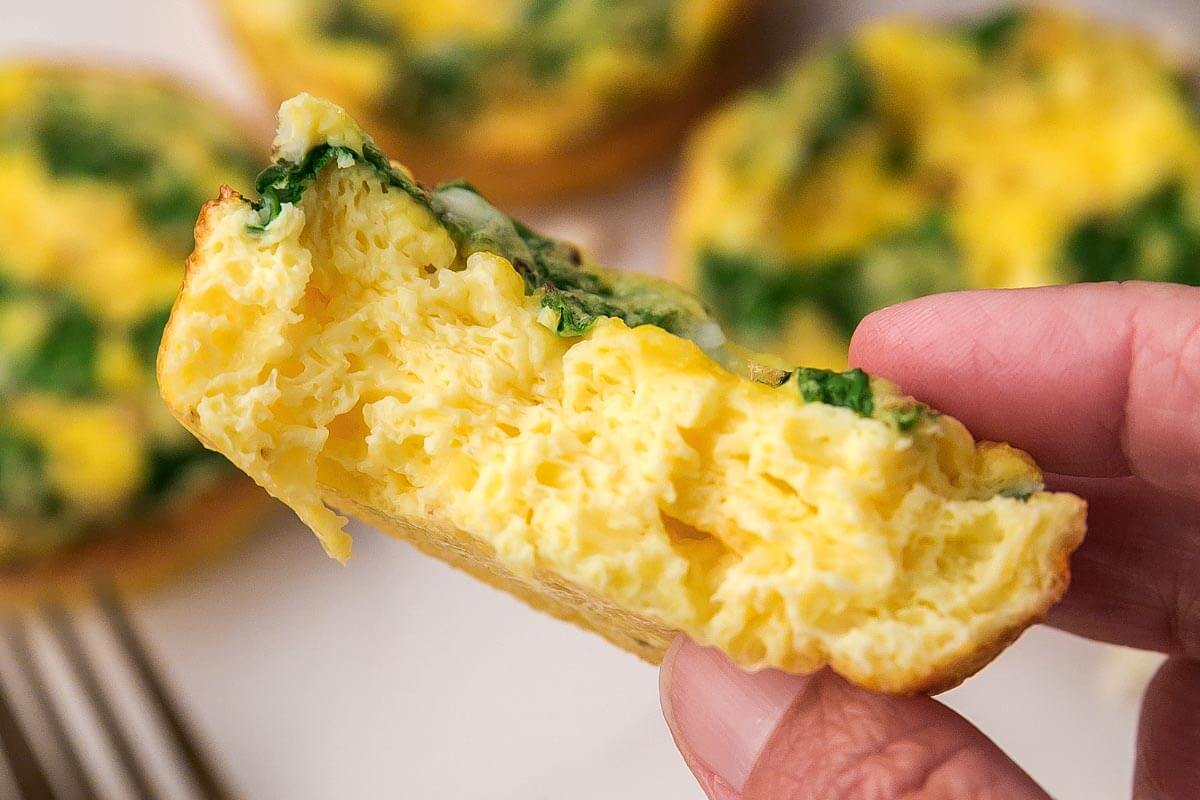 Spinach Feta Egg Muffin in hand with bite gone.