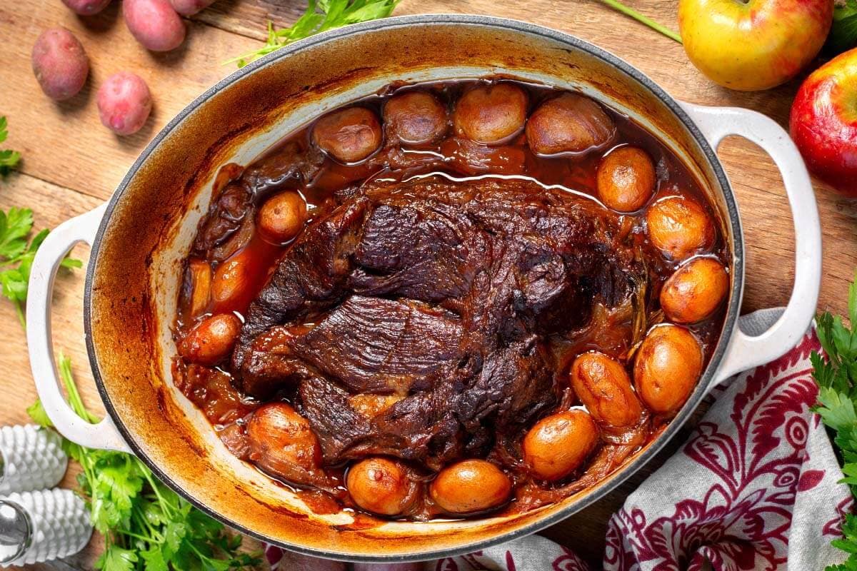 Apple Cider Pot Roast in a dutch oven with potatoes.