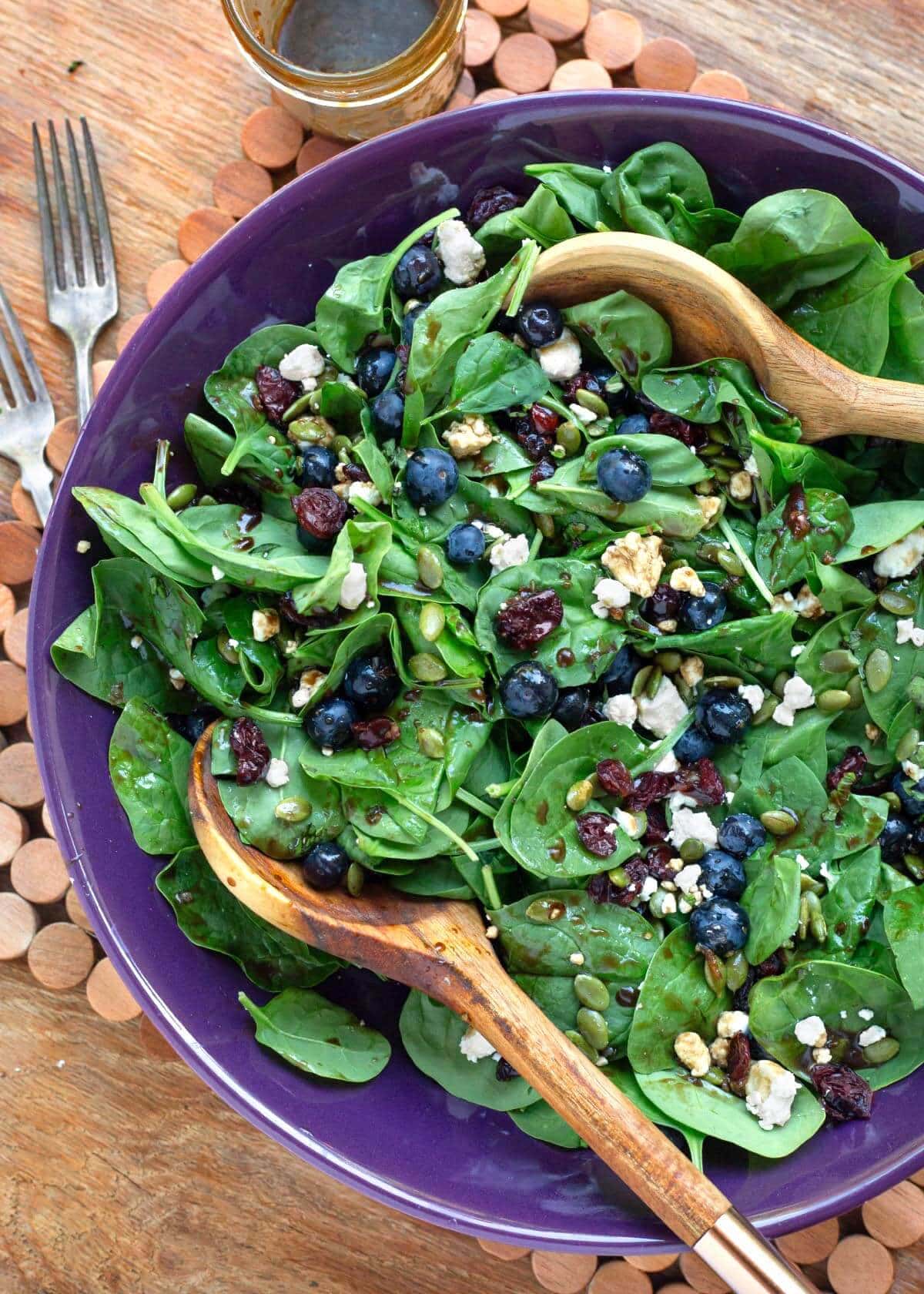 Blueberry Spinach Salad in a purple bowl with wood spoons