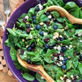 Blueberry Spinach Salad in a purple bowl with wood spoons