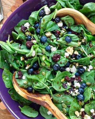 Blueberry Spinach Salad in a purple bowl with wood spoons