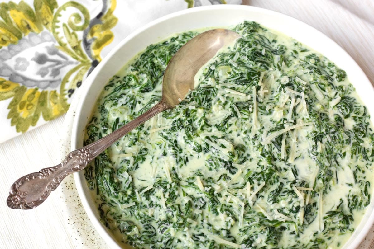 Cheesy Creamed Spinach in a white bowl with a spoon in it.