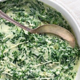 Cheesy Creamed Spinach in a bowl with spoon closeup.
