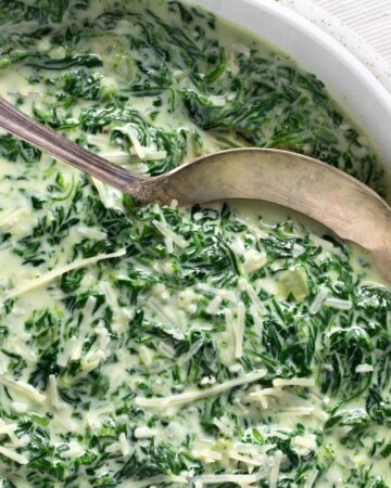 Cheesy Creamed Spinach in a bowl with spoon closeup.