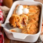 Crescent Roll Apple Dumpling on a spatula in front of pan of them.