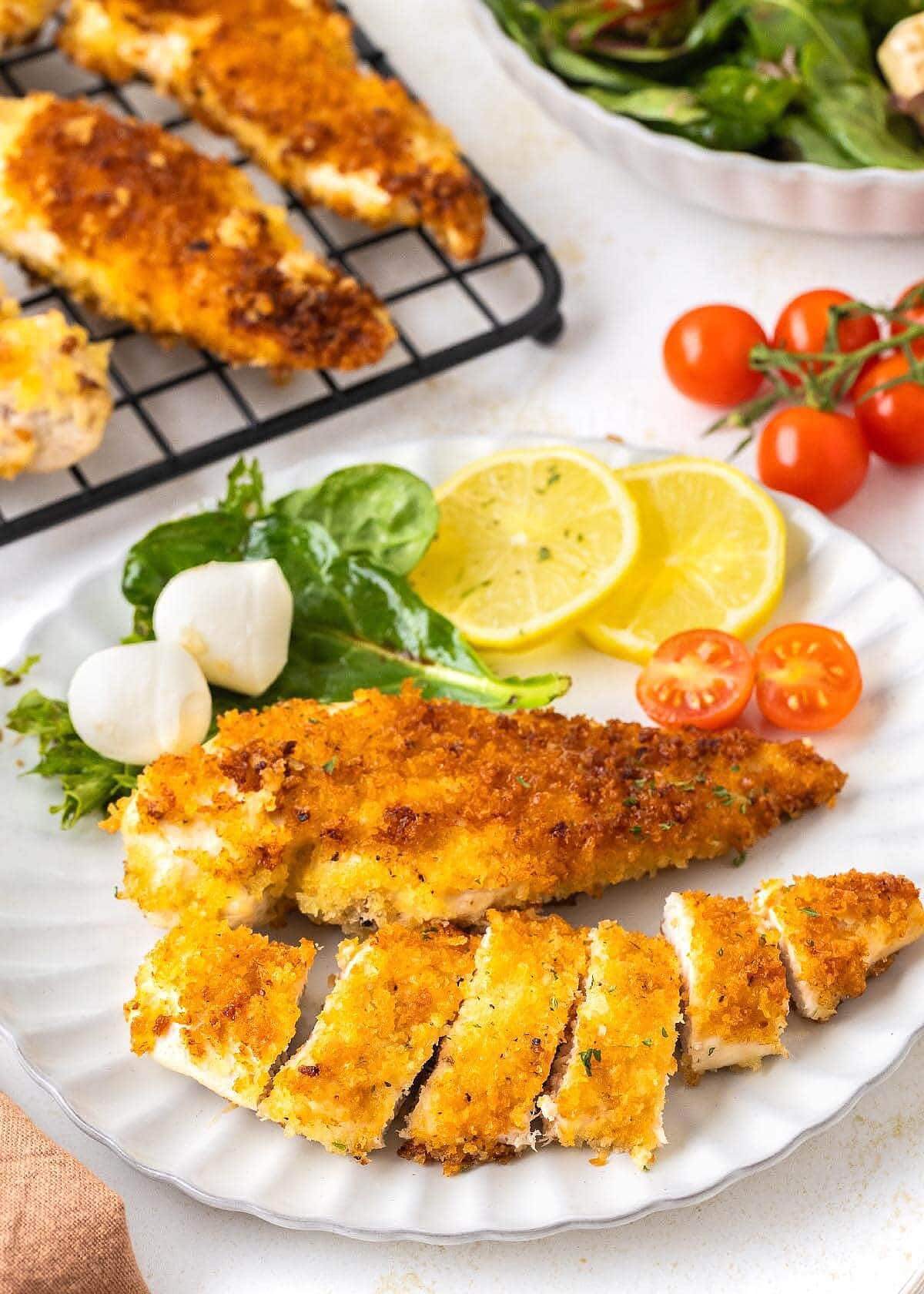 Crispy Pan-Fried Chicken Cutlets on a white plate with salad