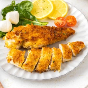 Crispy Pan-Fried Chicken Cutlets on a white plate with salad