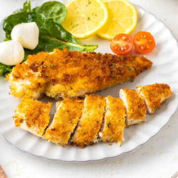 Crispy Pan-Fried Chicken Cutlets on a white plate with salad