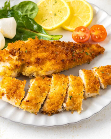 Crispy Pan-Fried Chicken Cutlets on a white plate with salad