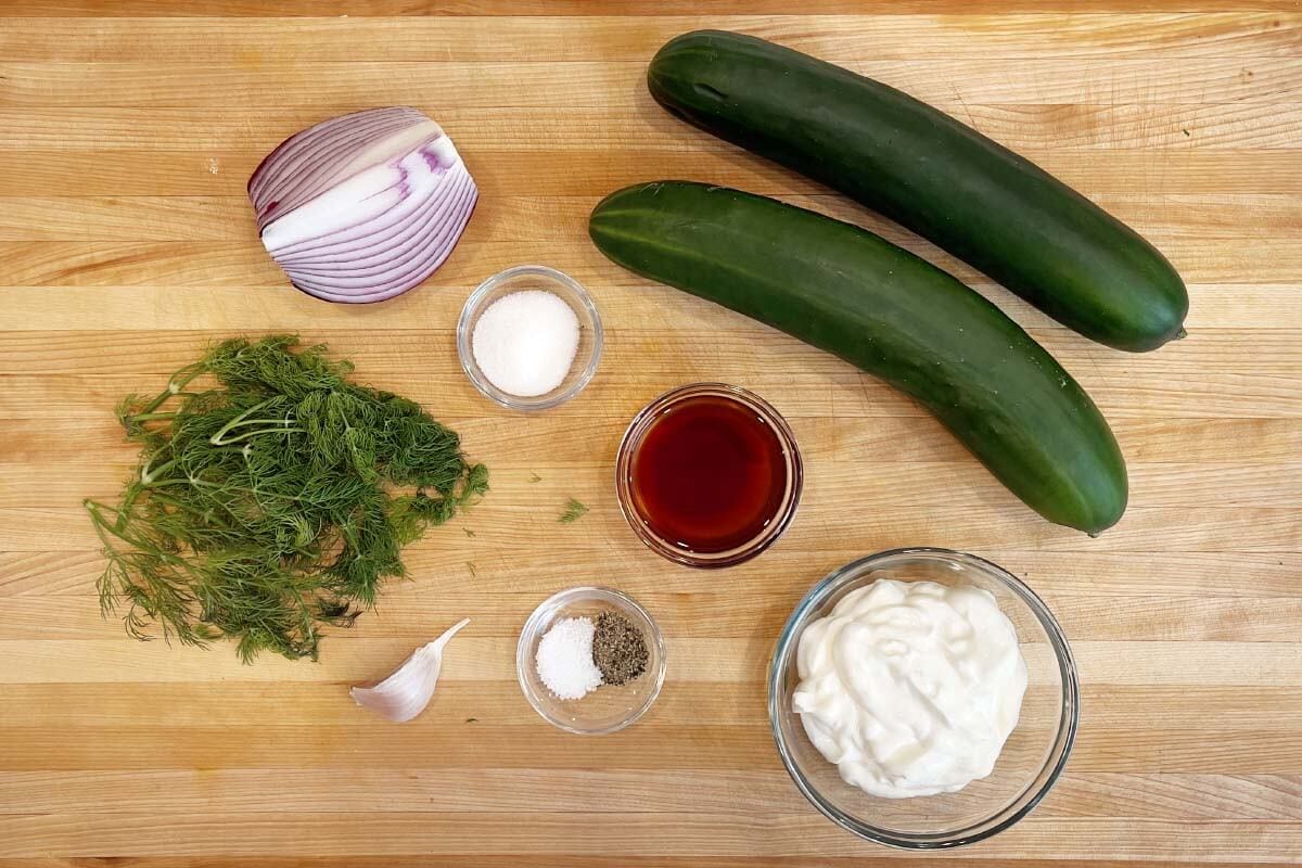 Creamy Dill Cucumber Salad ingredients on a board