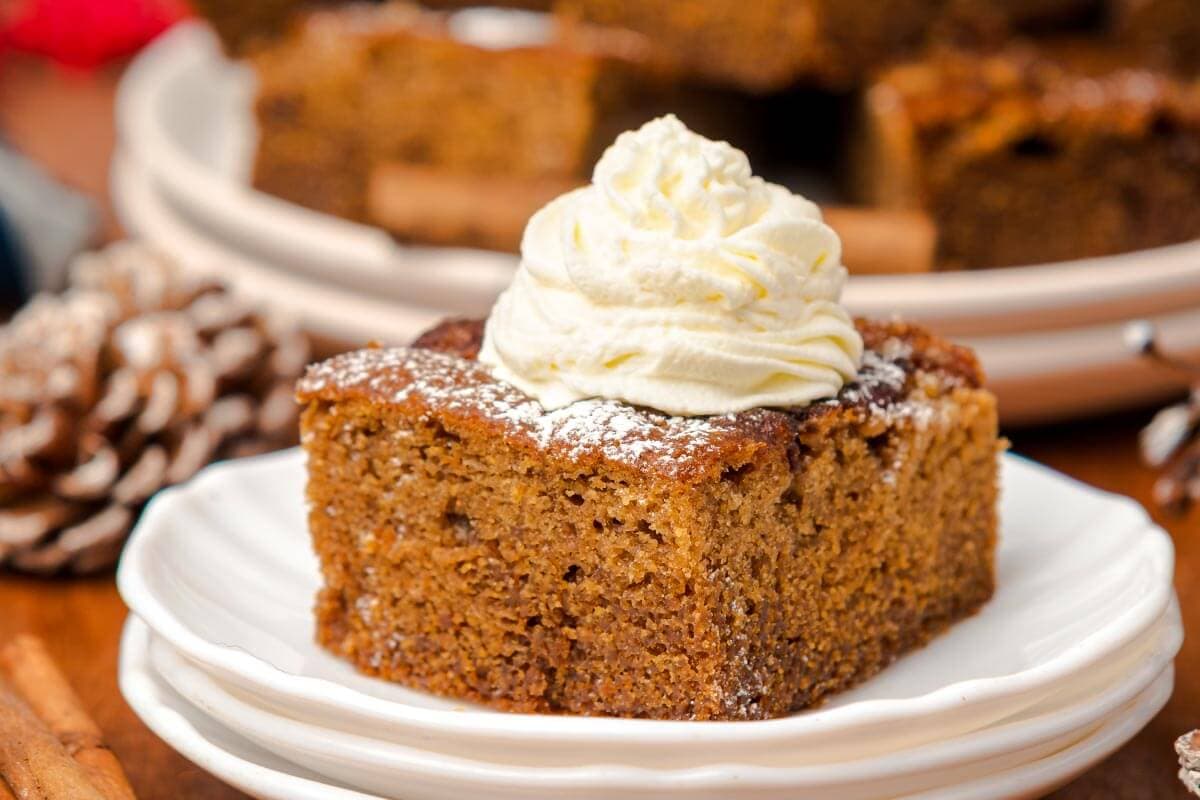 a piece of Old-Fashioned Gingerbread Cake with whipped cream on top