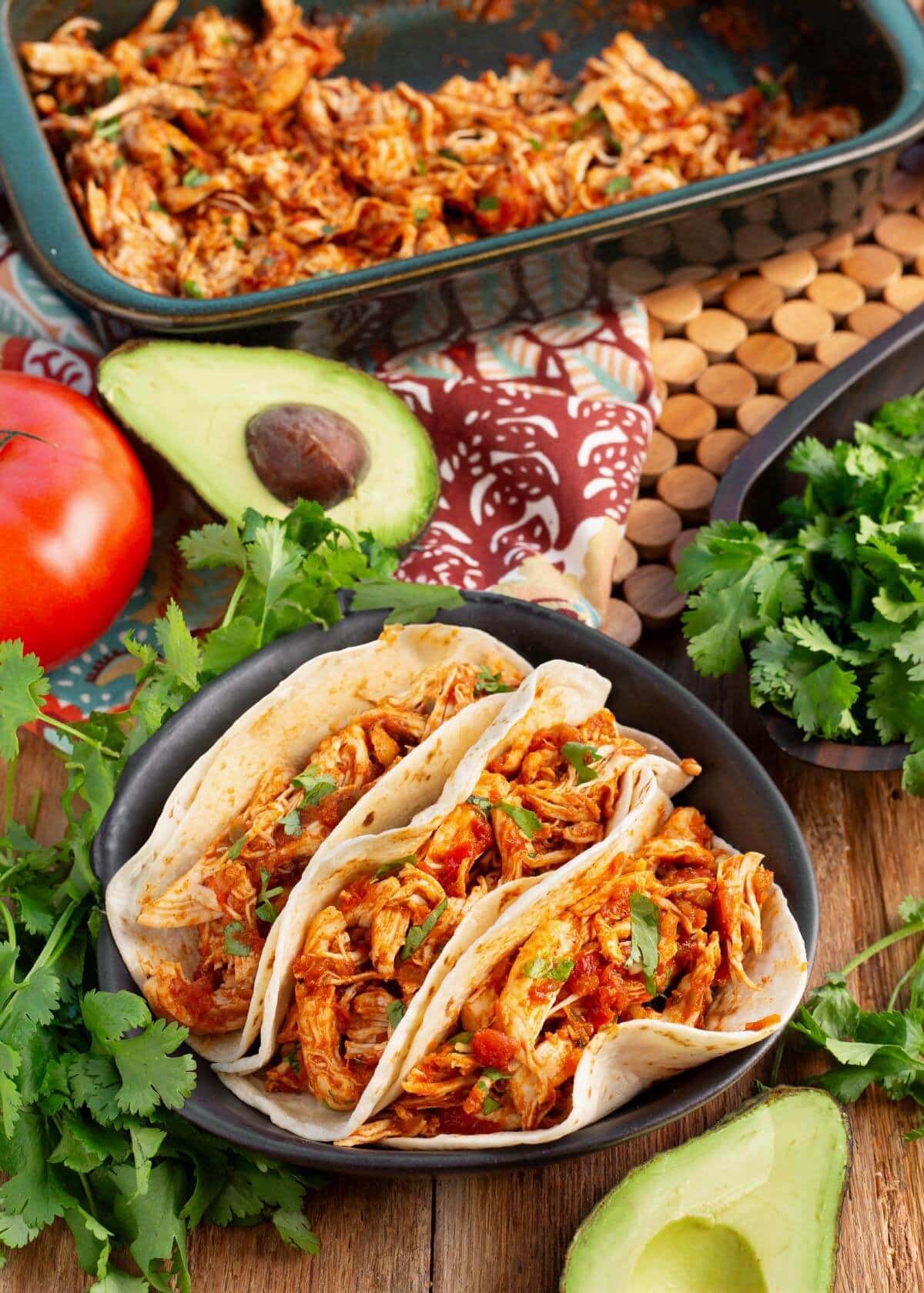 Easy Baked Salsa Chicken in tacos and in a pan with garnishes.