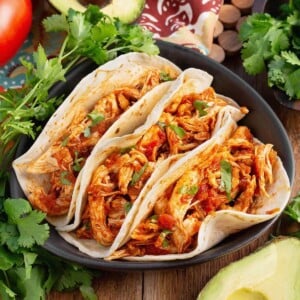 Easy Baked Salsa Chicken in 3 tacos on a plate with garnishes