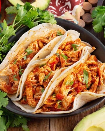 Easy Baked Salsa Chicken in 3 tacos on a plate with garnishes